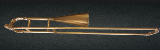 Golden handmade trombone in a greyish-black background.