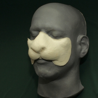 A foam latex rabbit nose prosthetic placed on a platic human face cast.