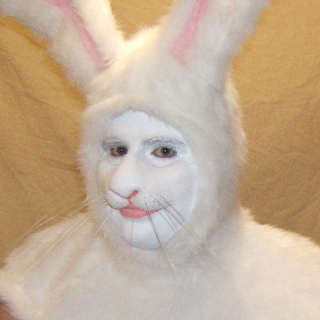 man wearing prosthetic makeup and a costume hood to look like a white rabbit.