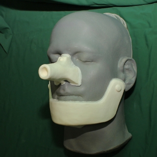 A foam latex prosthetic nose and chin of the Tin Man placed on a platic human face cast.