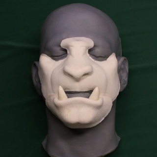A foam latex beast face prosthetic placed on a platic human face cast.