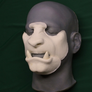 A foam latex beast face prosthetic placed on a platic human face cast.
