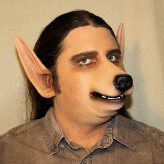 A man wearing a foam latex wolf muzzle and pointed ear prosthetics with makeup.
