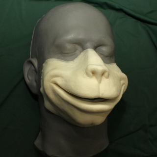 A foam latex monkey face prosthetic placed on a platic human face cast.
