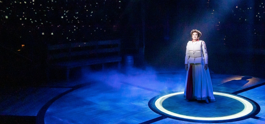 Production photo from The Unsinkable Molly Brown. A woman wearing a white life vest stands alone onstage in a spotlight.