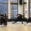 A group of dancers wearing black hats and black outfits performing a move.