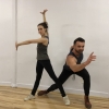 A female dancer with one arm up and one arm outstretched and a male dancer lunging forward with his arm outstretched.